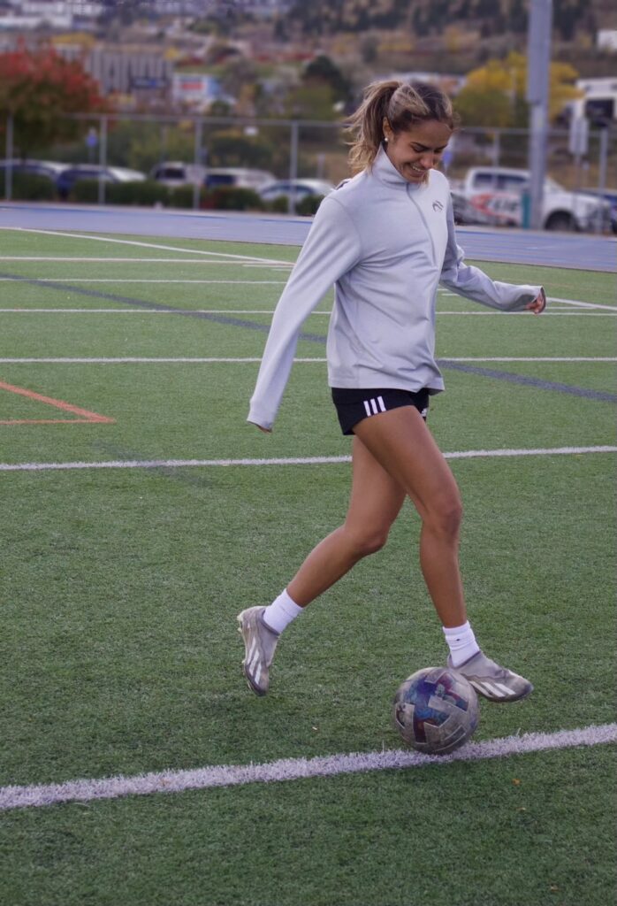 Raiya smiling while dribbling the soccer ball on the field